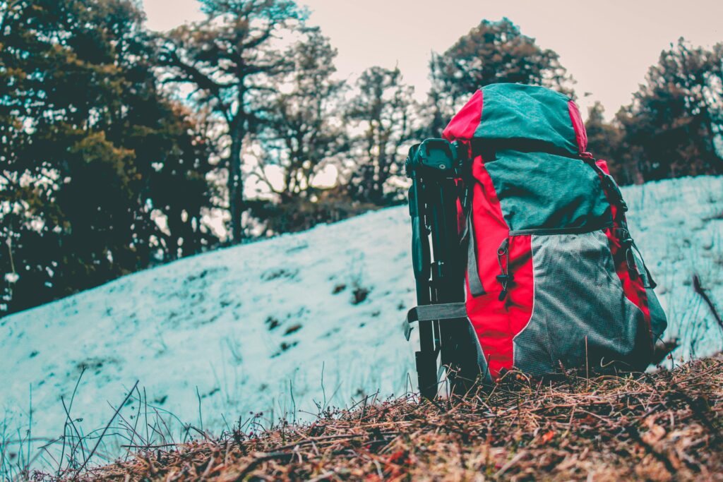 A vibrant backpack rests on a snowy trail in Shimla. Perfect for adventure and nature enthusiasts.