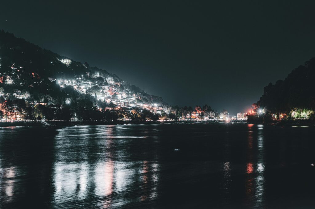 Stunning nighttime view of Nainital Lake with the illuminated town reflecting in the water.