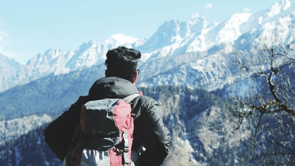 A backpacker admires the snowy peaks in Shimla, India, capturing the essence of adventure and nature.