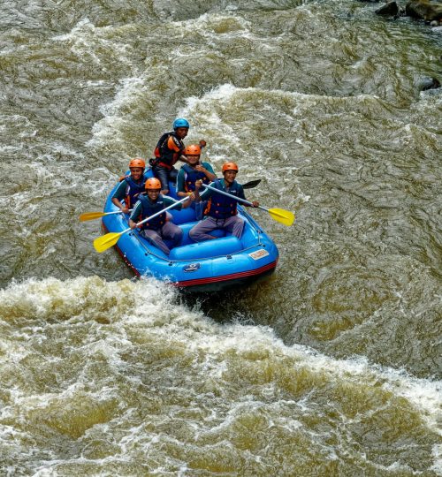 Group of adults rafting in Cikidang, West Java, showcasing teamwork on rough waters.